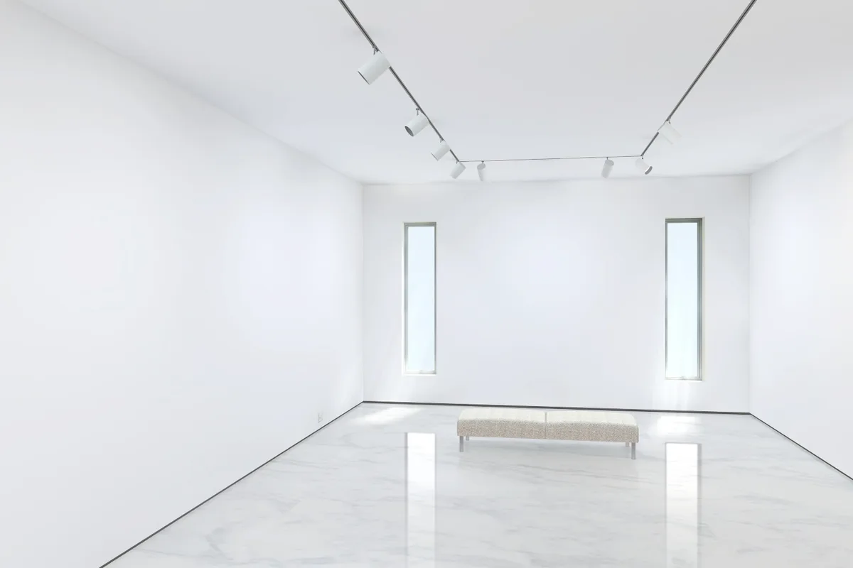 An empty Exhibbit gallery room with marble floor and track lighting