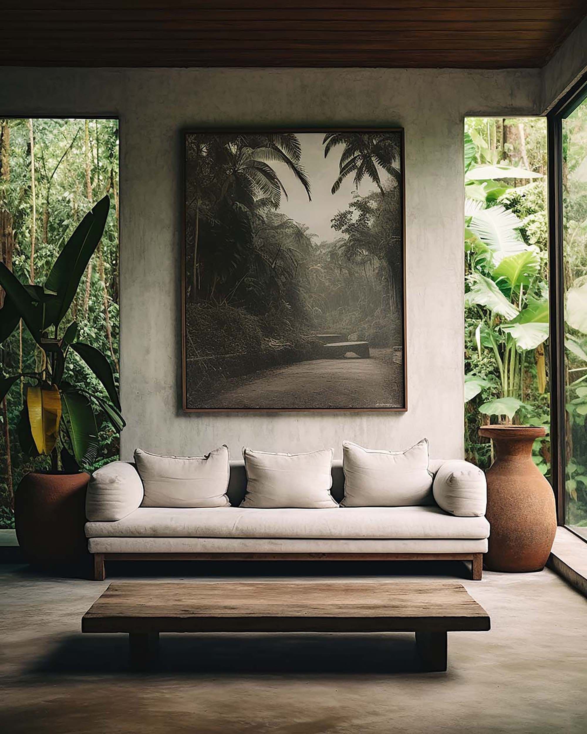 Modern living room with a large wall frame above a cream sofa, flanked by tall windows and potted plants.