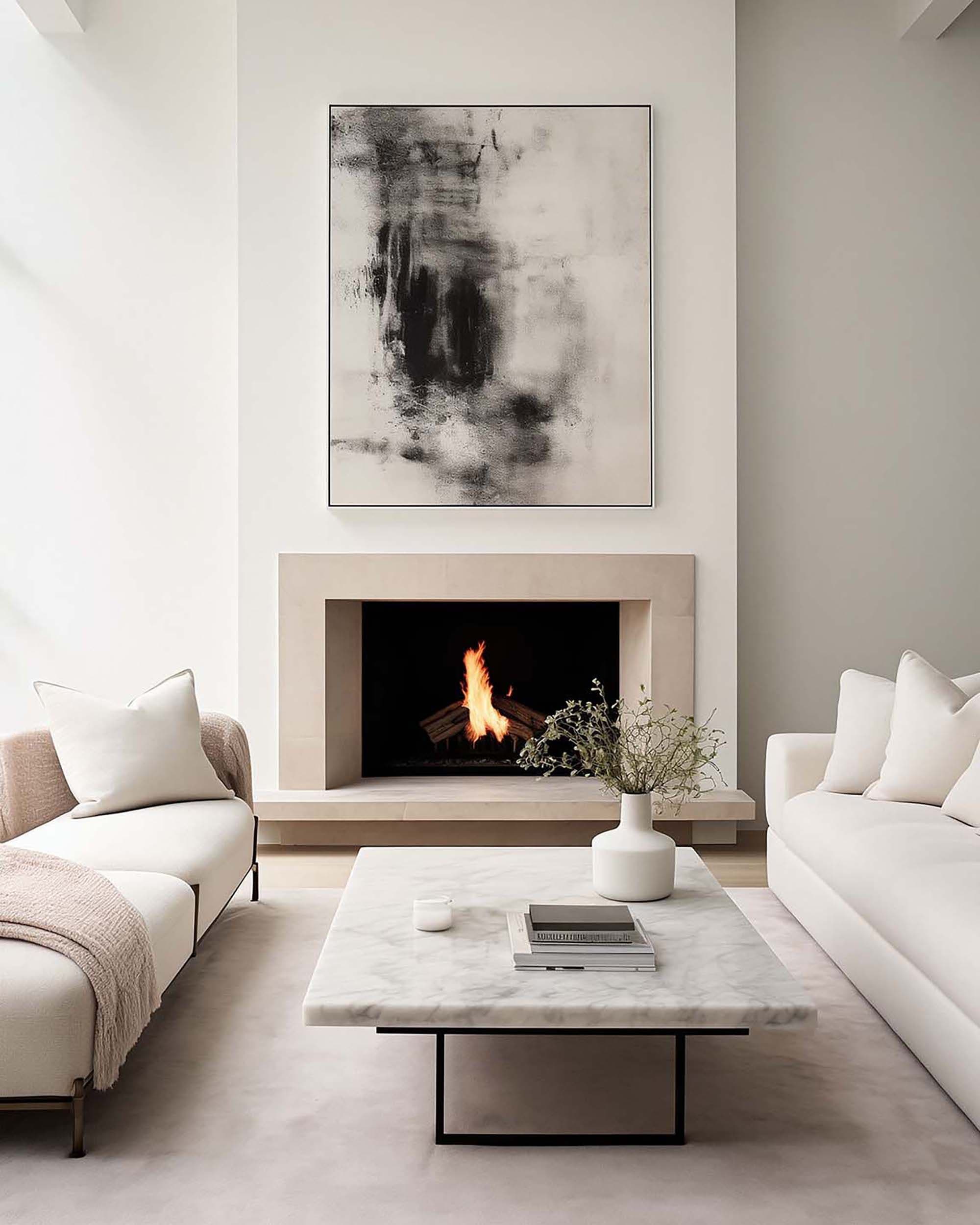 Minimalist living room with a framed wall piece above a stone fireplace, flanked by light sofas and a marble coffee table.