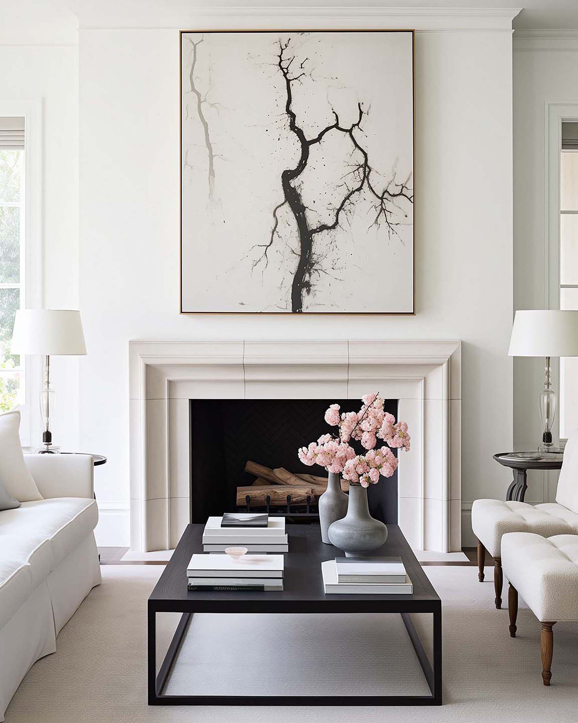 Living room wall art centered above a white fireplace mantel, with a black coffee table and pink flowers below.