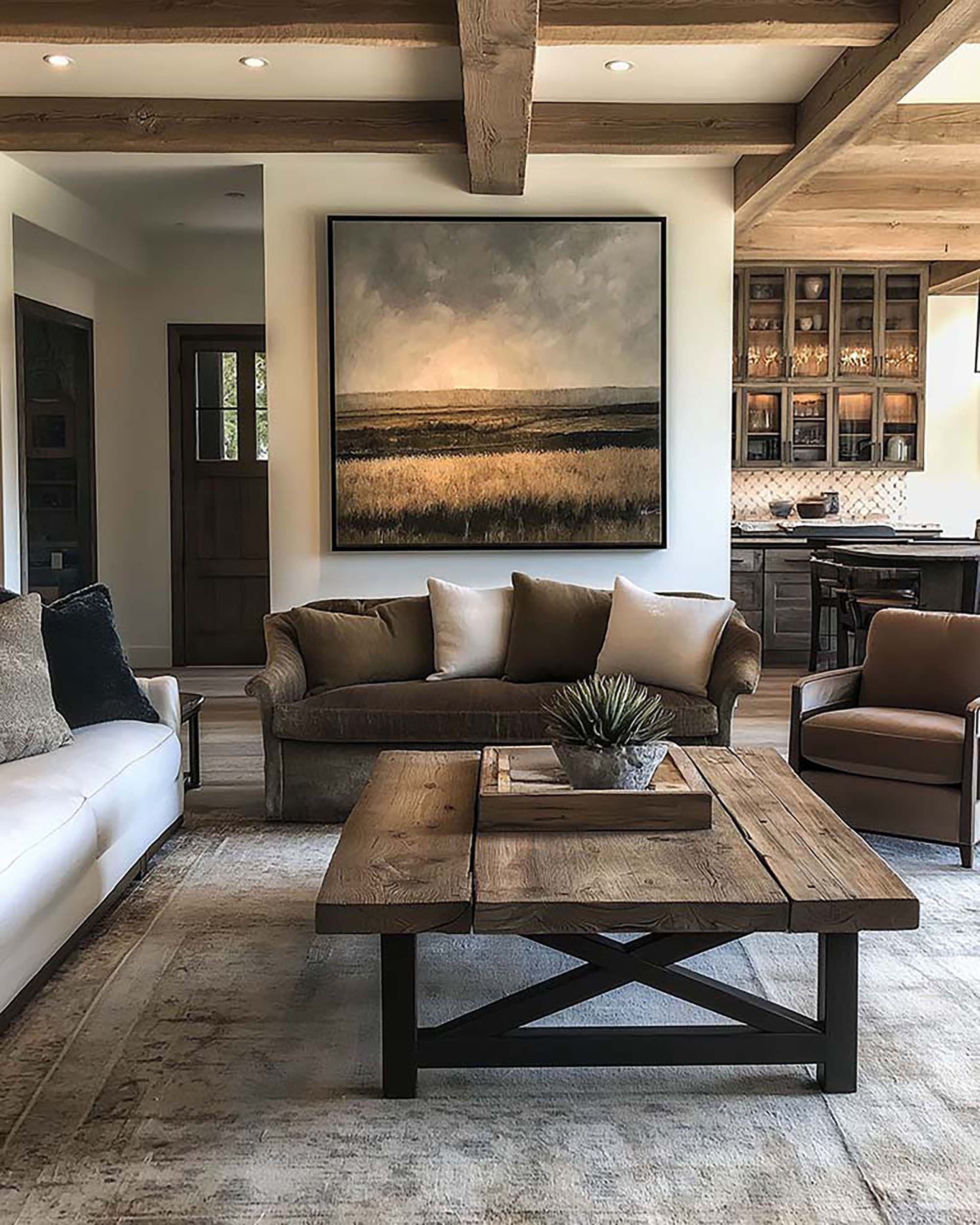 Rustic living room with exposed wood beams and a large framed artwork above a brown sofa and wood coffee table.