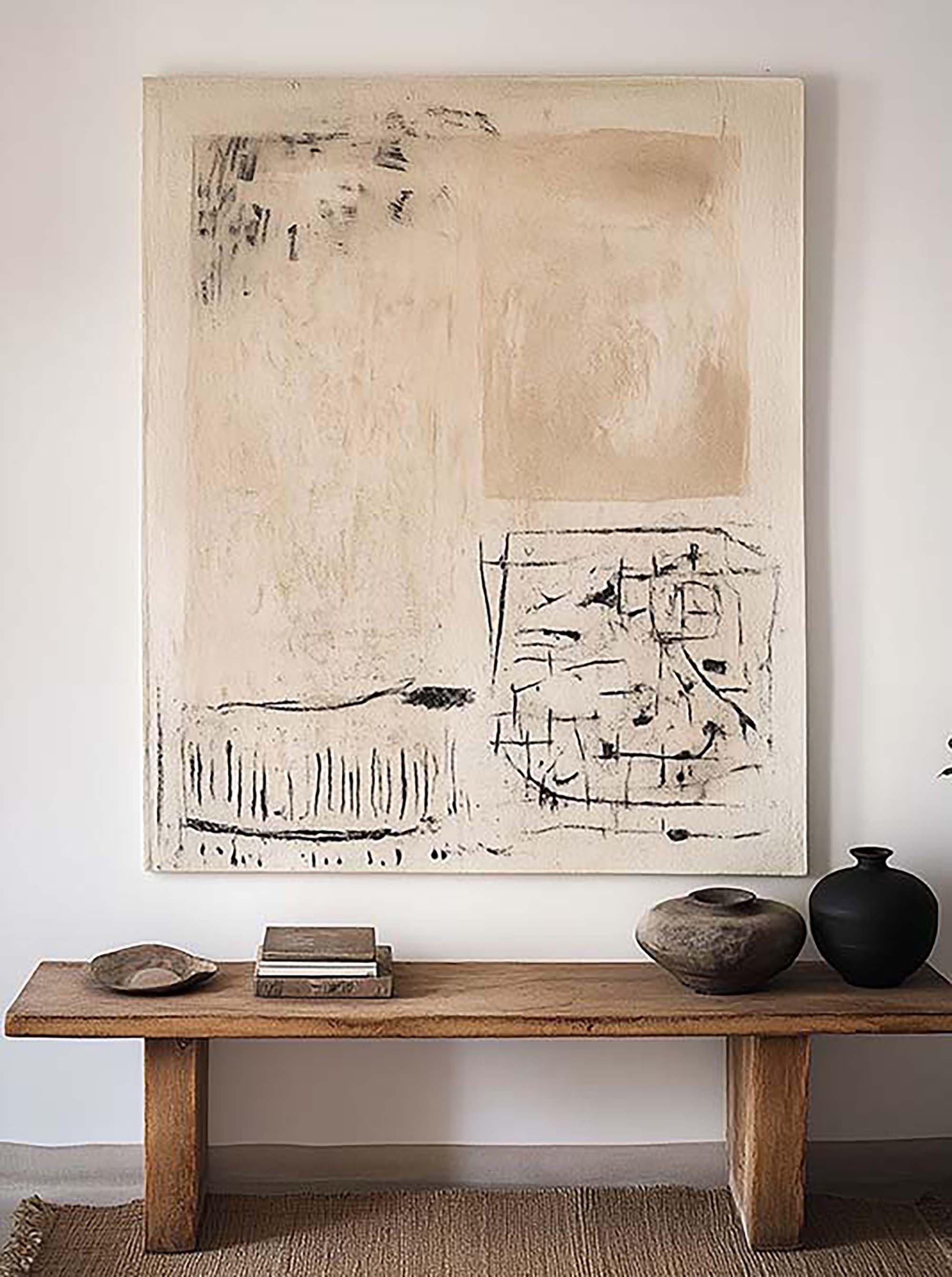Minimal entryway wall with a large customizable frame above a warm wood console table with stacked books and two ceramic vases.