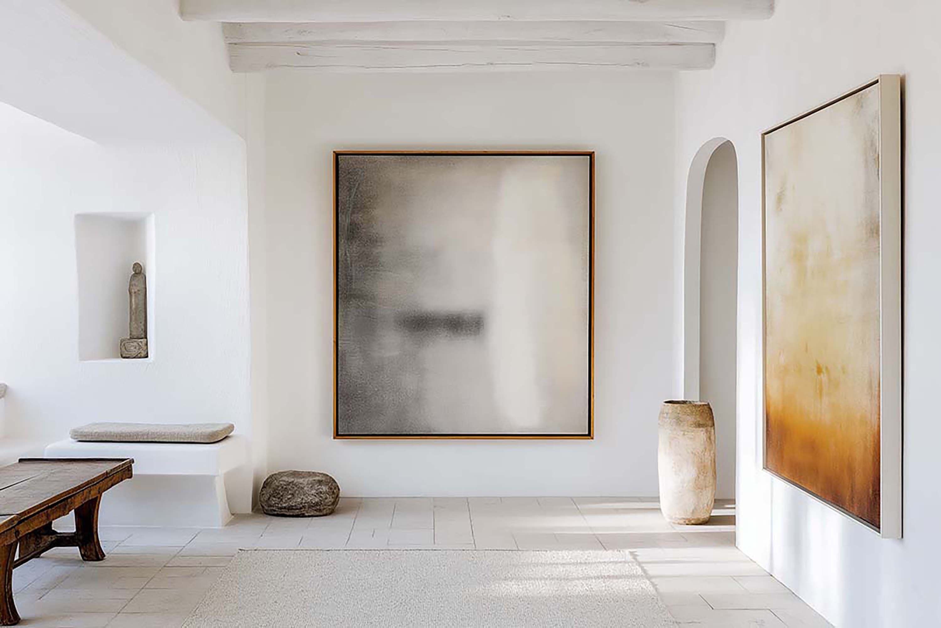 Bright minimalist hallway with a large square frame on a white wall, arched doorway to the right, and a built-in bench.