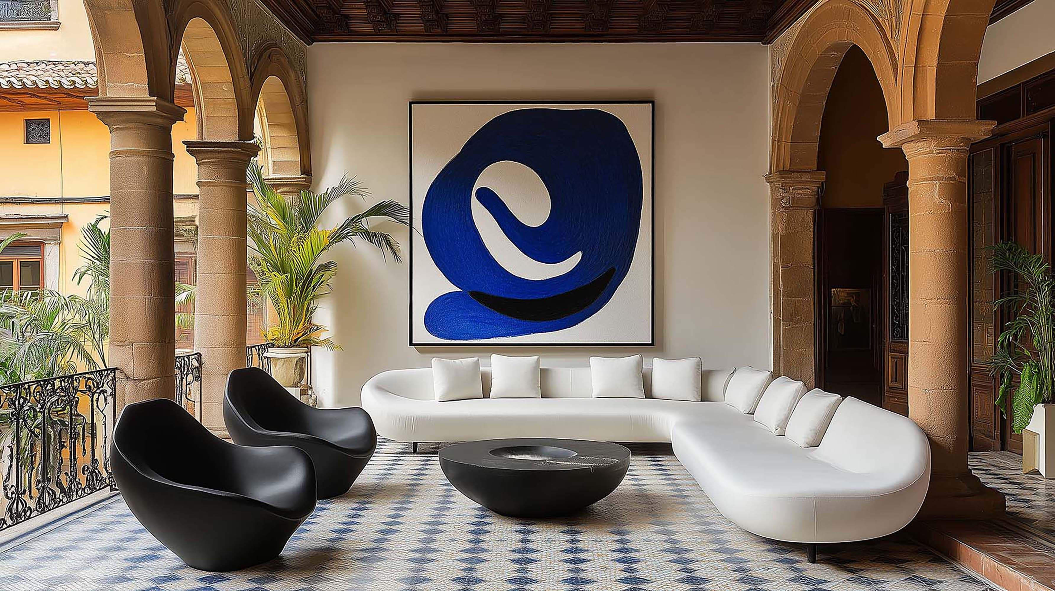 Covered courtyard living room with a large framed artwork above a white curved sectional and a low round coffee table.