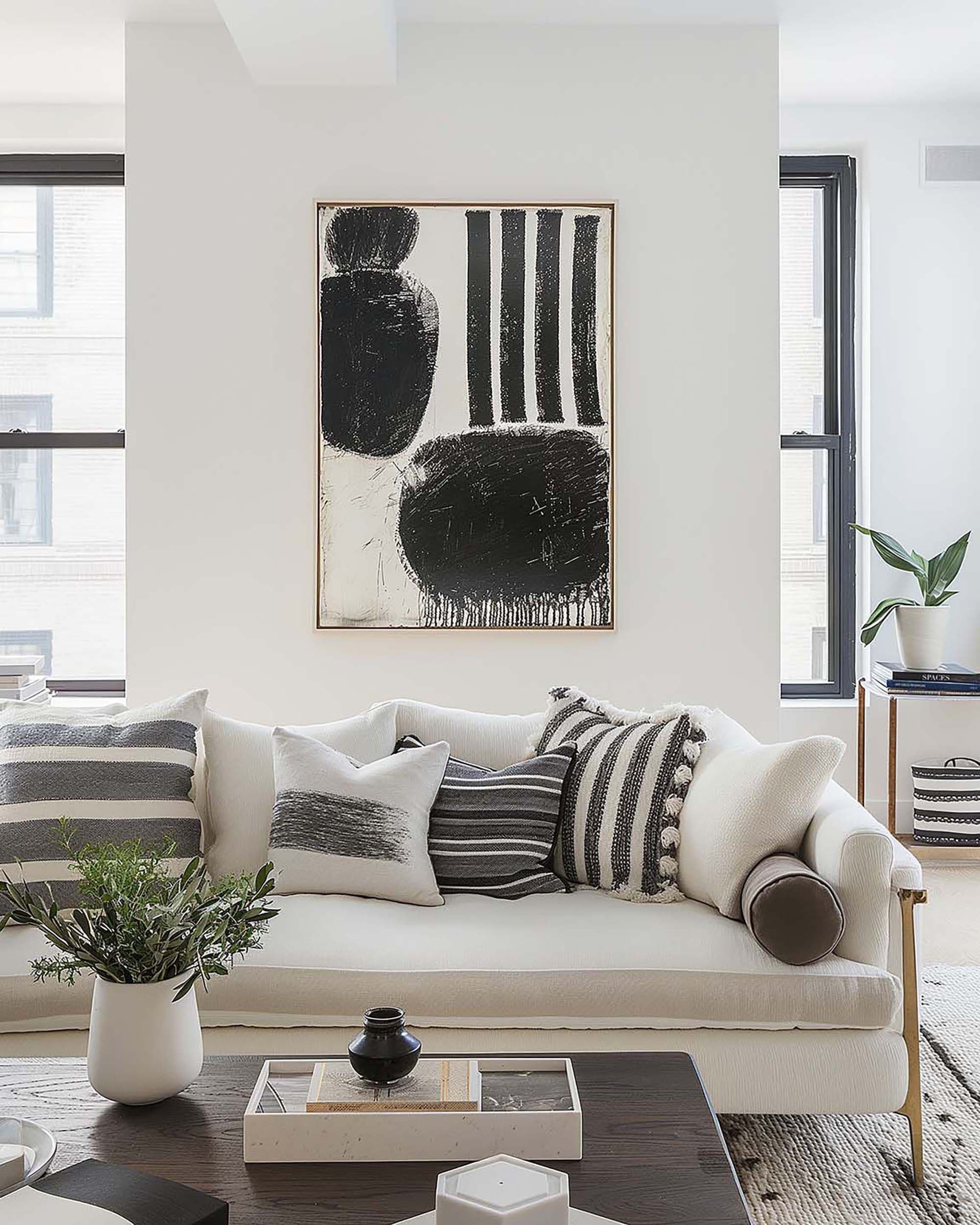 Bright modern living room with a large framed artwork centered above a white sofa and a dark wood coffee table.