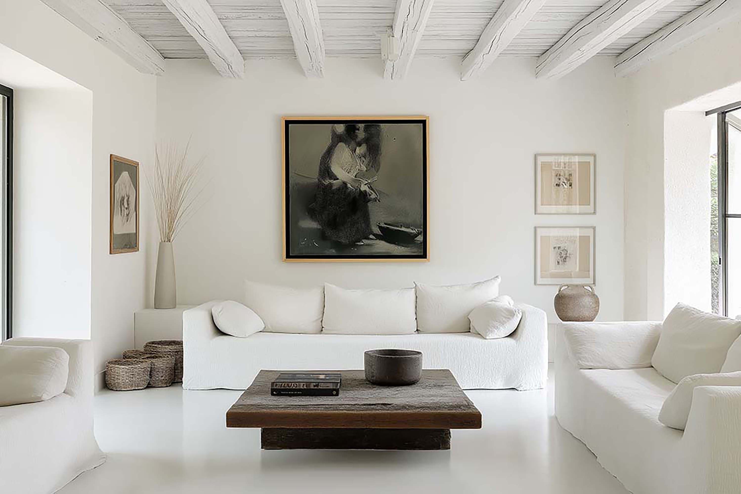 Minimal living room with a large framed piece centered above a white sofa, facing a low wood coffee table.