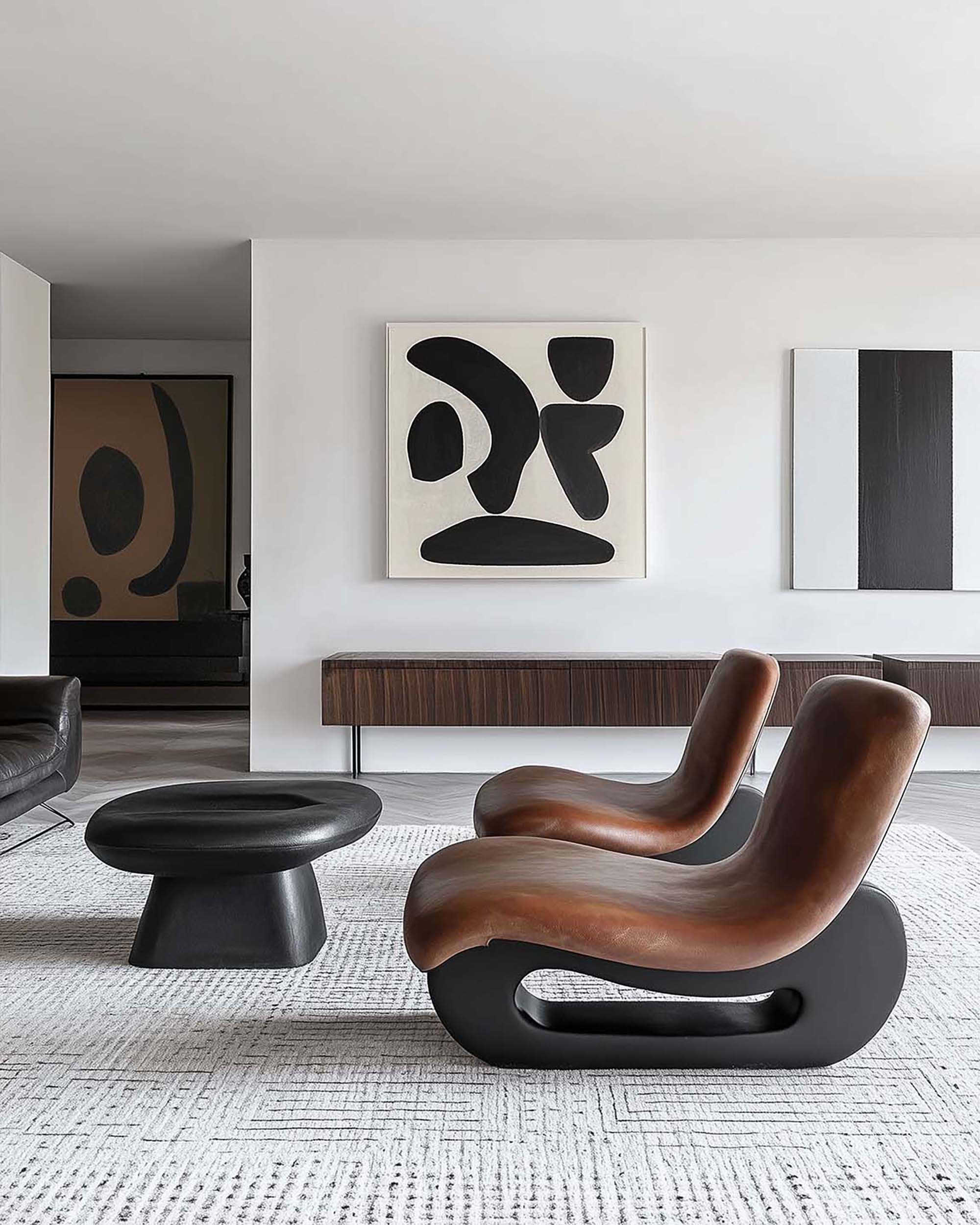 Modern living room with a square frame centered above a long floating wood console, with two sculptural lounge chairs in front.
