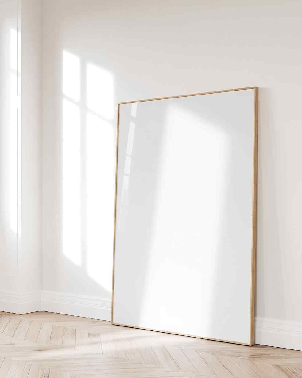 Bright minimalist hallway corner with a large light-wood frame leaning against a white wall above herringbone floors.