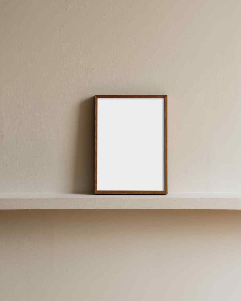 Leaning wooden frame on a shallow wall shelf against a warm beige wall in a minimalist hallway-like space.