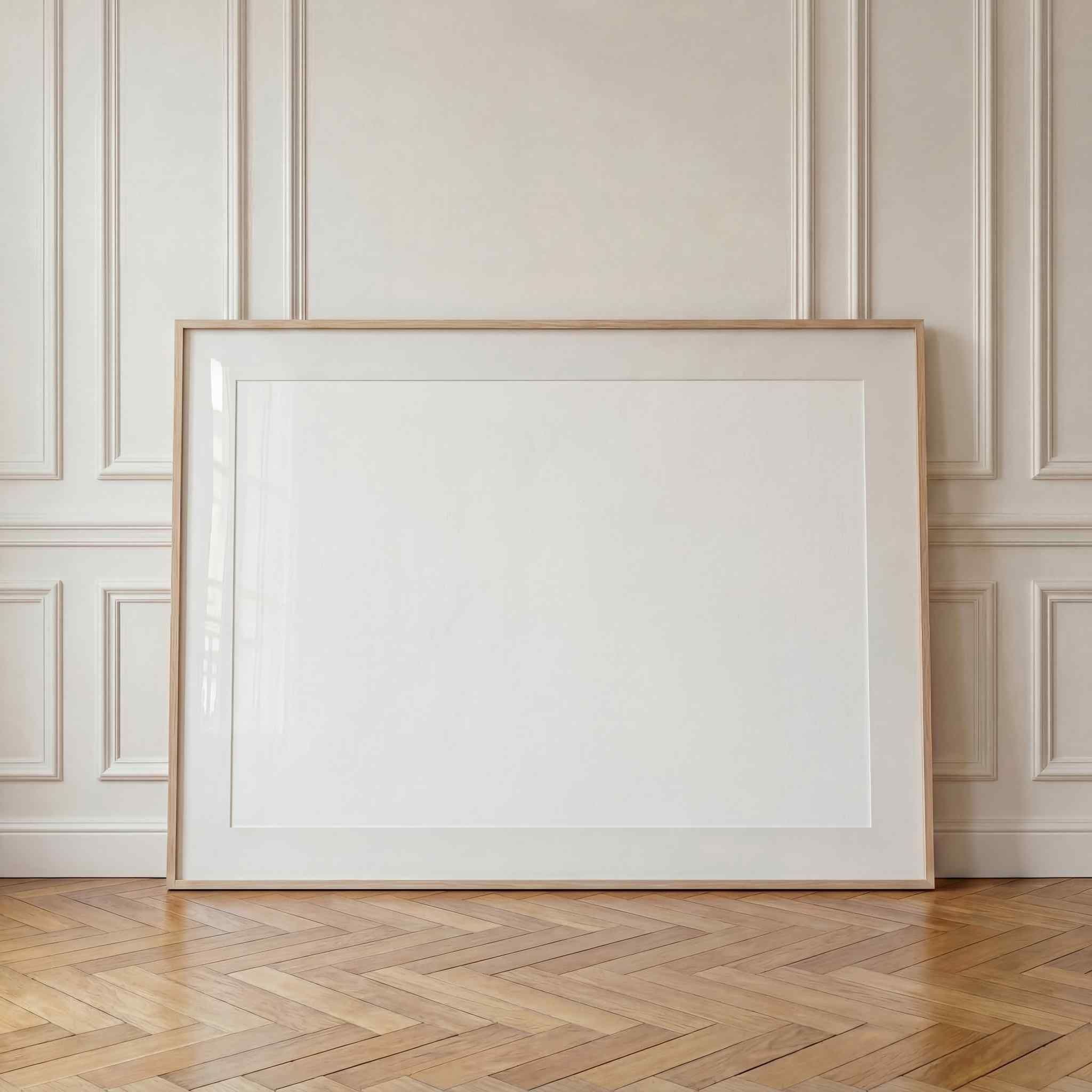 Large horizontal frame leaning against a white paneled living room wall above warm herringbone wood flooring.