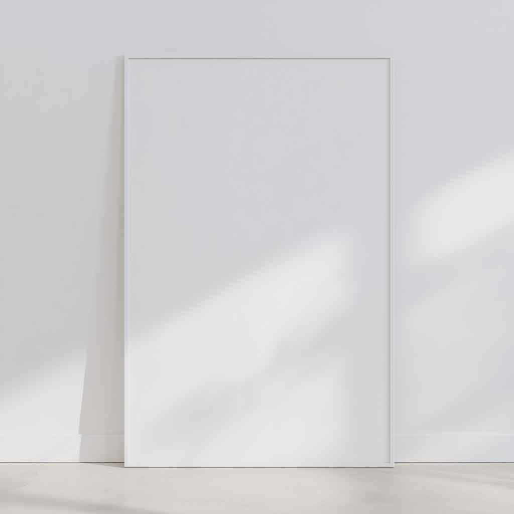 Minimal studio wall with a large white frame leaning on the floor against a white wall in soft daylight.