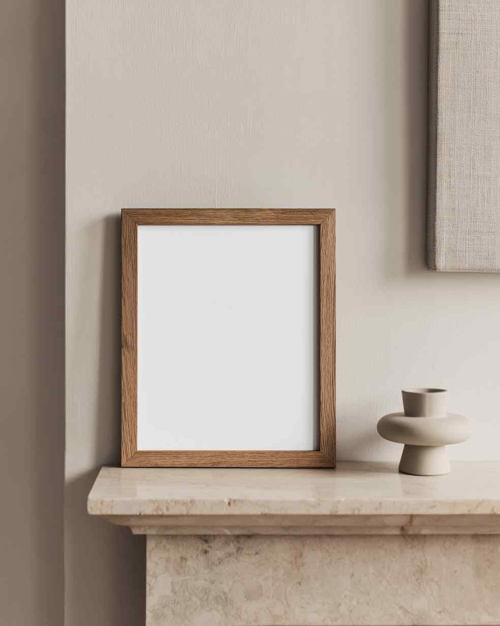 Minimal living room mantel with a leaning wood frame on a light stone ledge beside a small ceramic vase.