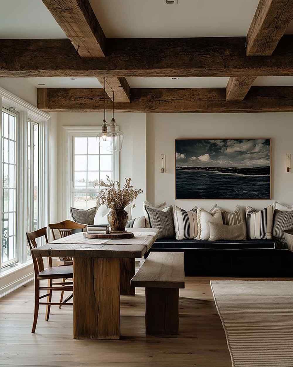 Dining room with a wall-mounted framed artwork above a built-in bench seat, with a wood table and pendant lights.