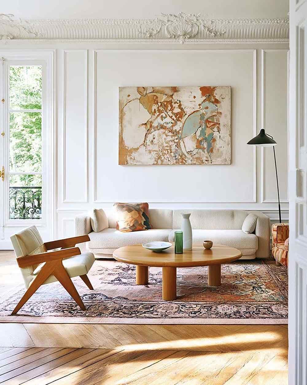 Bright living room with white wall molding and a large horizontal artwork above a cream sofa, beside a black floor lamp.